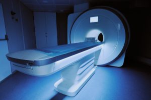 MRI scanner standing in hospital room with examination table extended, showing advanced medical imaging equipment used for diagnostic purposes in healthcare setting